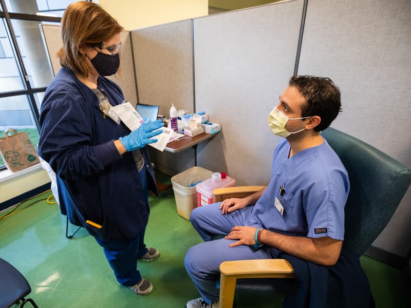 Nursing Instructor Marlie Farrar, left, shares information with OB-GYN resident Dr. Ahmed Zaki Moustafa before administering a dose of COVID vaccine.