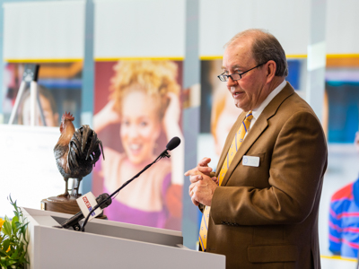 Pat Busby, president of Century Club Charities, speaks before a backdrop of images of Children's of Mississippi patients.