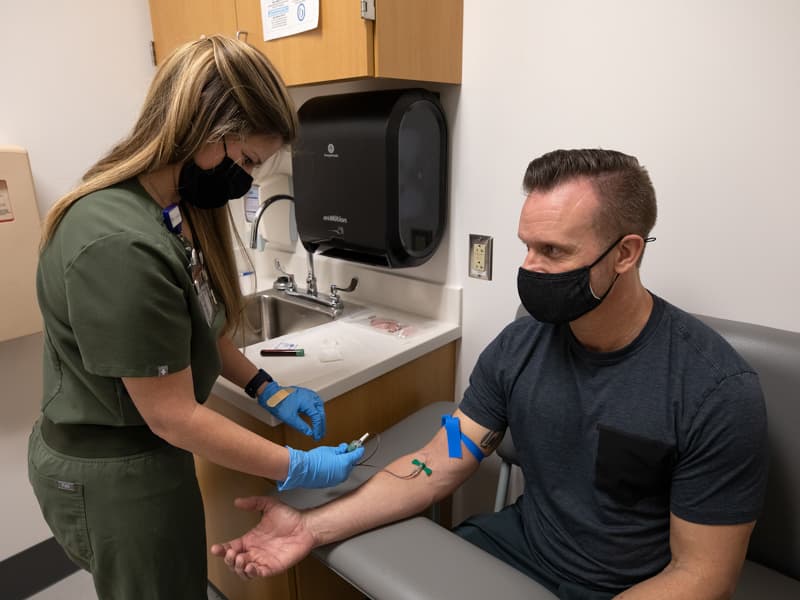 Angelena Sharp, a clinical research nurse, completes a blood draw from Keith Hodges, a research participant in the Clinical Research Trials Unit.
