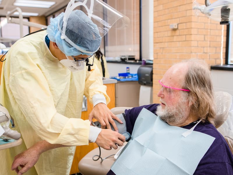 Third-year dental student Thien-Trieu Nguyen takes the blood pressure of patient Coleman Williamson before beginning a dental exam.