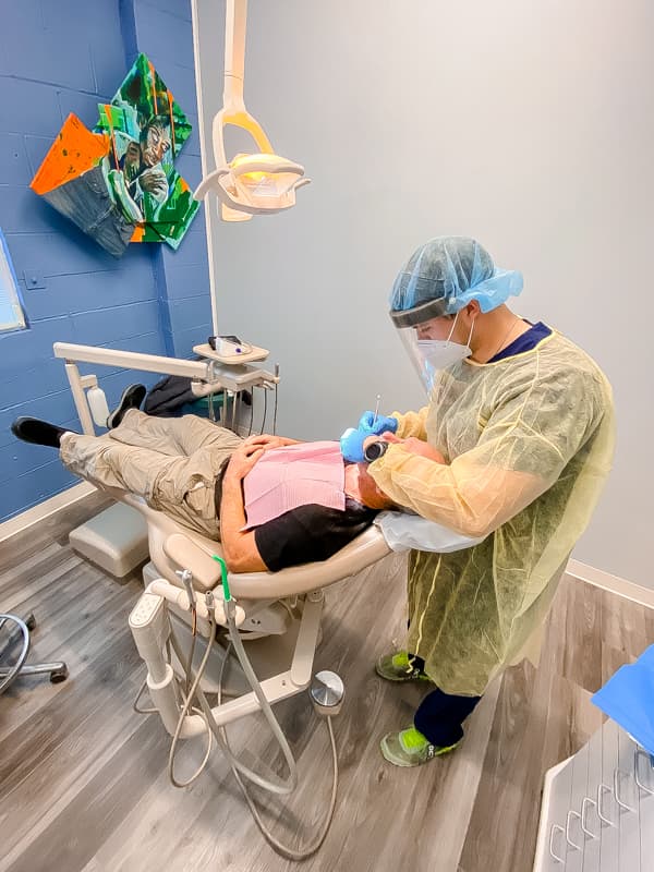 Dental student Hayden Coffey peers into the mouth of patient Donald Cook.