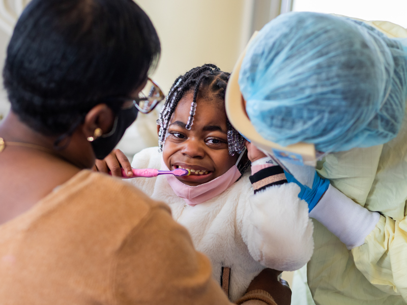 Dr. Bit Na Lee, a pediatric dentistry resident, gets a peek at Shameeka Goodman's tiny teeth as Shameeka's mother, Vickie Goodman, holds her in the Pediatric Dentistry Clinic.