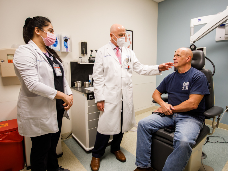 Rinki Varindani Desai, adult outpatient lead speech-language pathologist, and Dr. Randall Jordan check Dereck Moore's facial function.