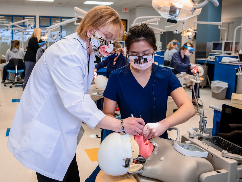 Dr. Sandra Horne, professor of dental hygiene, checks the work of student Elaina Lam during Dental Hygiene Instrumentation class.