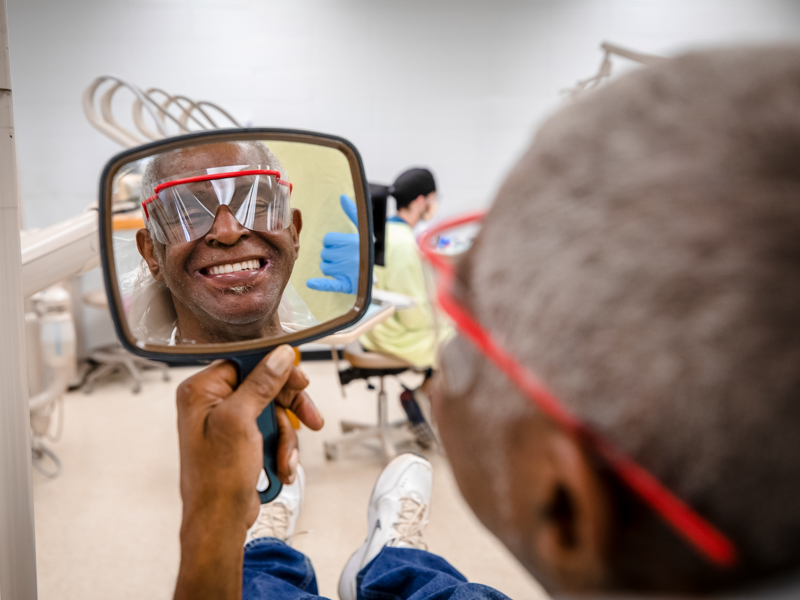 Wilbert McGee inspects his new dentures crafted by Trent Johnson, School of Dentistry student.