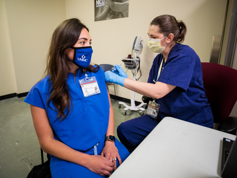 Dr. Josie Bidwell, right, associate professor of preventive medicine, administers a second dose of the Pfizer COVID-19 vaccine to Currie Fletcher, physical therapist.