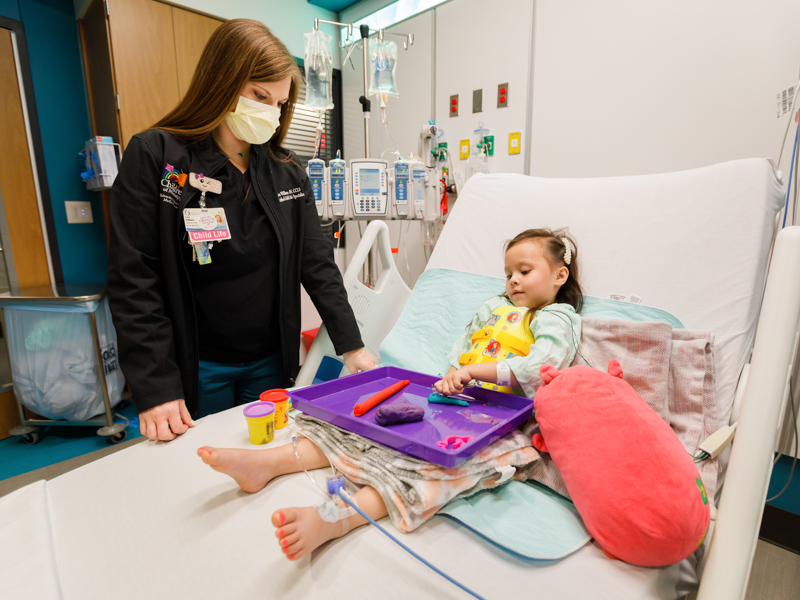 Child life specialist Cara Williams helps patient Elena McBroom of Vicksburg strengthen her motor skills through therapeutic play.