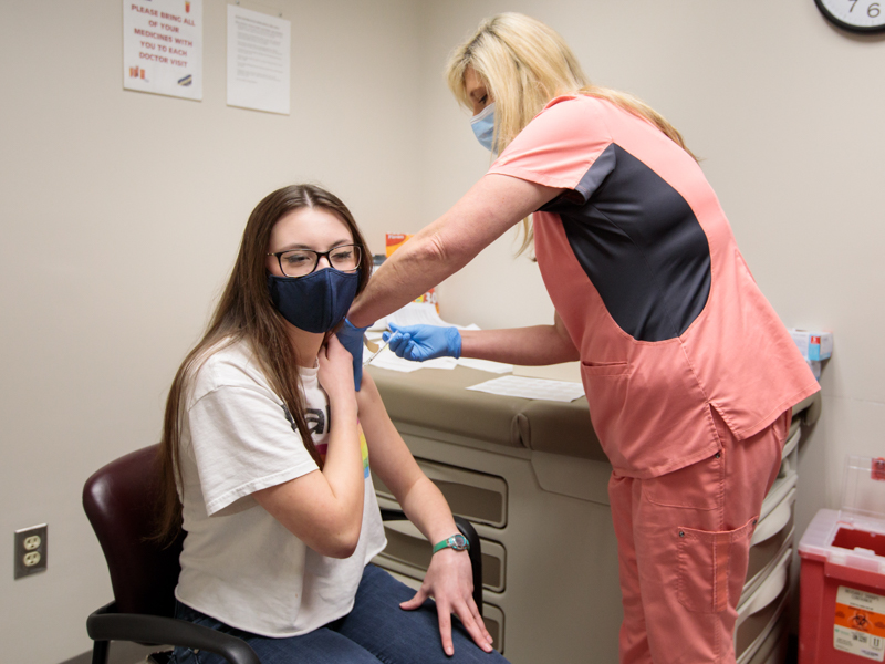 Rosemary Williamson, 14, a Clinton resident, winces as Kate Morgan, ambulatory nurse, administers a dose of the Pfizer-BioNTech vaccine.