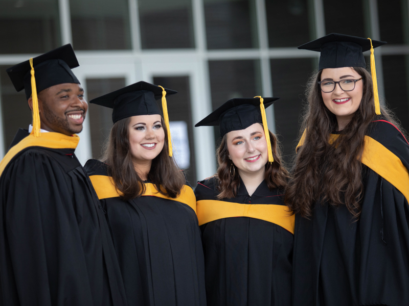 School of Graduate Studies in the Health Sciences students, from left, Bobby Cavett Jr., Sydney Reaves, Kayla Patterson and Lucy Taylor pose for a photograph prior to UMMC commencement ceremonies May 28 at the Mississippi Coliseum.