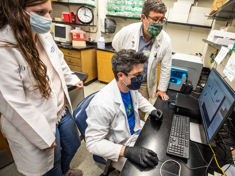 Microbiology PhD students Kristianna Felch and Jonathan Crider look over flow cytometry data with Dr. Stephen Stray. Stray serves on the dissertation committee for multiple doctoral students in addition to teaching.