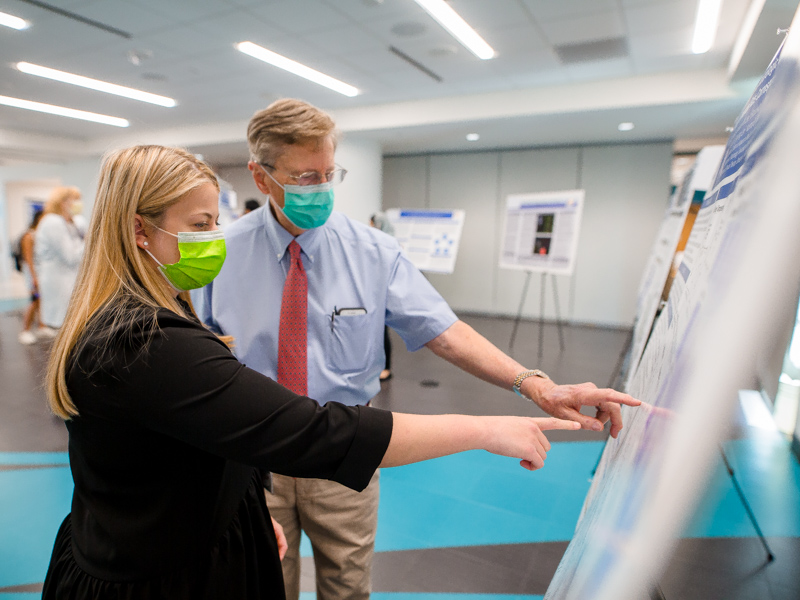 Third-year neonatology fellow Dr. Caroline Glendye shows her research poster to her father, Dr. Fred Kuhn.