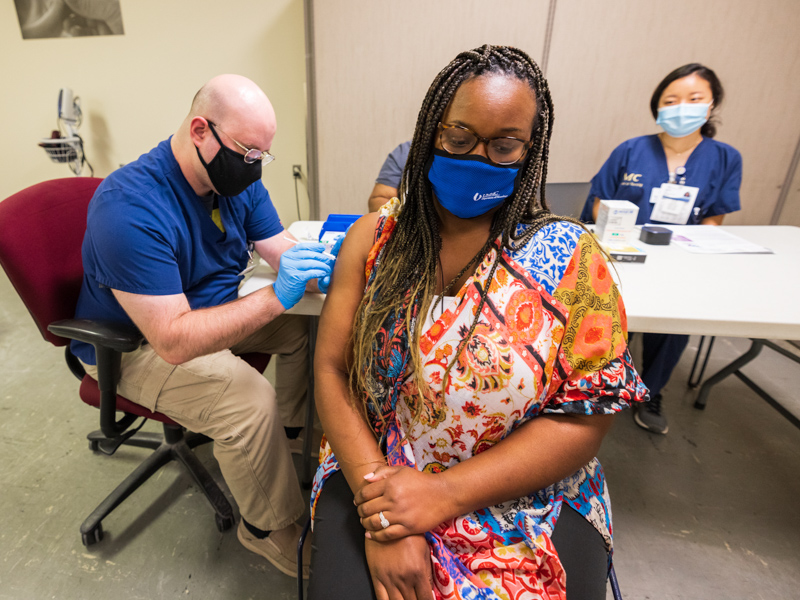 Licensed practical nurse Robert Roka gives Natasha Hamlin her COVID-19 vaccination Thursday in the Medical Center's vaccine clinic.