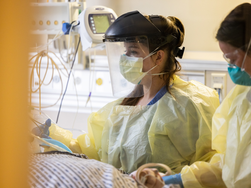 Medical ICU registered nurse Cassie Coats assists as a team moves a COVID-positive patient into a new bed.