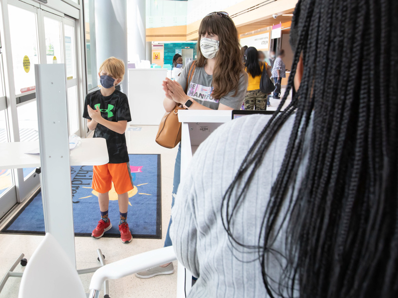 Children's of Mississippi safety screener and greeter Shaunace Lodge checks in Jennifer Floyd and her son, Oliver, by asking a series of health questions and promoting hand-sanitizing before entering.