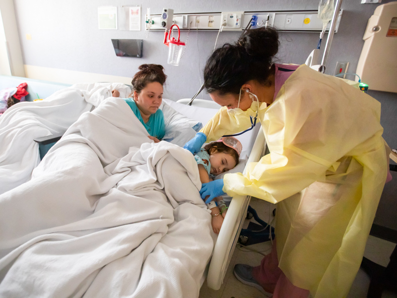 Registered nurse Leslie Parnell checks on sleeping MIS-C patient Emma Corley of Lumberton as her mother, Crystal Head, looks on.