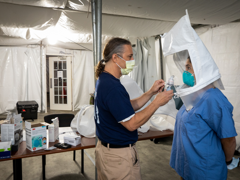 David Reed, left, of Pittsburg, and Maria Agresta Workman, of Maryland, members of the federal response team, check personal protective equipment prior to patient arrival at the monoclonal antibody infusion clinic for COVID-19.