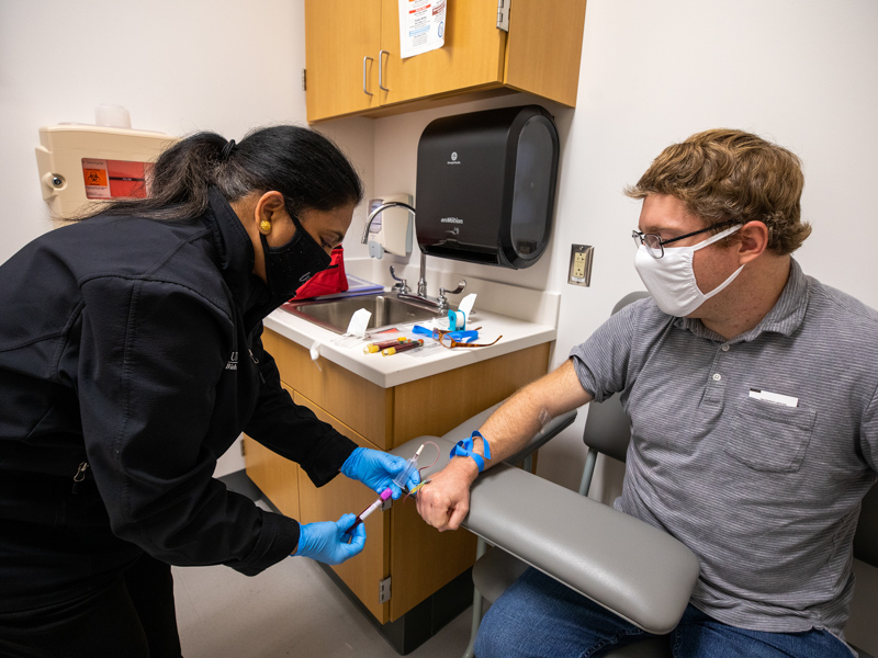 Shukla Faruque, a participant recruiter for the UMMC Biobank, draws blood from Joshua Ingram in the Clinical Trials and Research Unit. UMMC's adult and pediatric COVID-19 biobanking project enables research on the disease throughout its progression and recovery.
