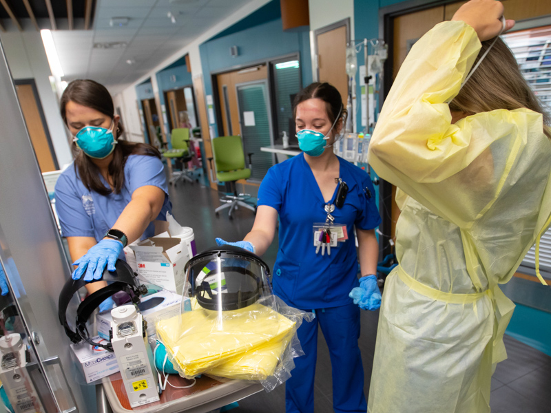 Registered Nurses Haley Williams, left, and Abagael Mathis, center, sanitize their PPE shields after checking on a COVID-19 patient in pediatric intensive care at Children's of Mississippi.