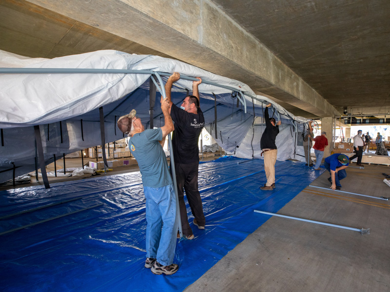 From left, Billy Lewis of Colonial Heights Baptist Church helps Mark Randolf of Samaritan's Purse raise the walls of a field hospital Monday at UMMC.