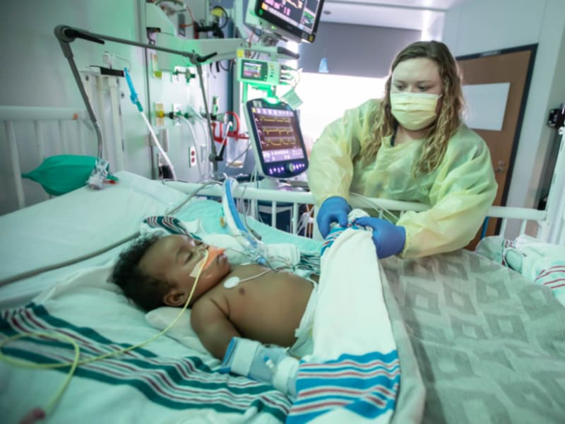 Four-month-old Ravontae Robinson breathes with the help of a ventilator. Millie Grace Lafayette, a pediatric intensive care unit inpatient nurse, checks his heartbeat in the Kathy and Joe Sanderson Tower at Children's of Mississippi.