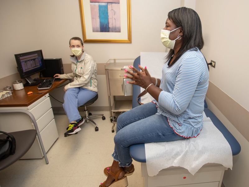 Dr. Allison Strickland talks with Felicia Beasley, right, at her trans radial web surgery follow-up appointment.