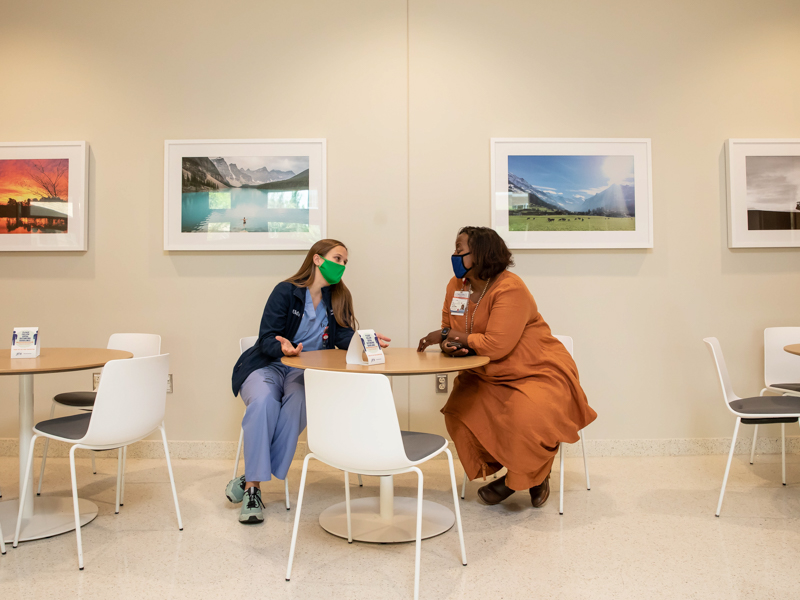 Dr. Loretta Jackson, vice dean for medical education, and third-year medical student Mary "Alex" Fratesi, who headed the committee that chose the photos for the exhibit, “Color Our Walls,” take a break near the Medical Education Building coffee shop, where some of the images are displayed. Twelve photos are hanging throughout the ground level of the building.