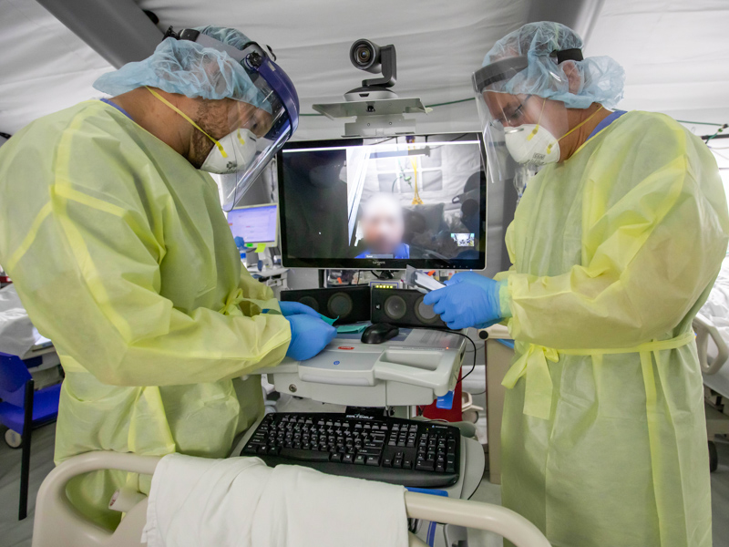 Peter Holz, left, a registered nurse and assistant medical director for the Samaritan's Purse field hospital on the UMMC campus, and John Freyler, family care coordinator for Samaritan's Purse, facilitate a telehealth visit between a patient and the patient's family member.