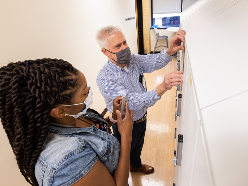 Steven Moseley, director of dental ambulatory operations at the School of Dentistry, and DeLandra Cook, an administrative assistant in the school's Clinical Affairs office, place a plaque bearing the name of a donor on the front of a student locker.