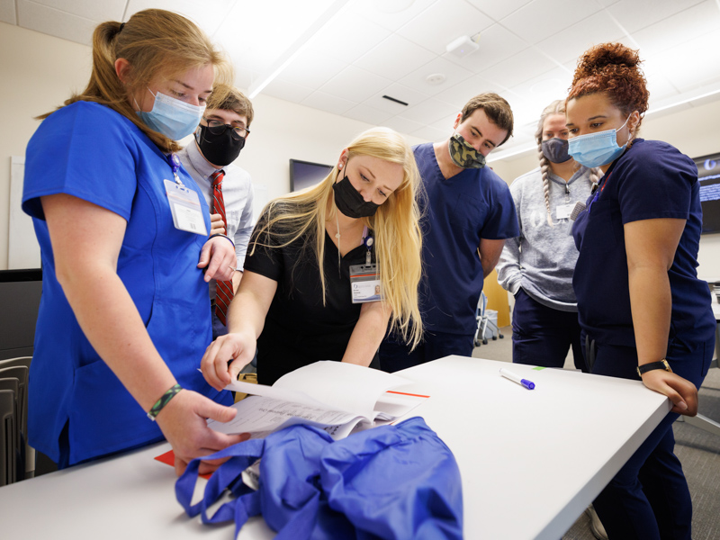 From left, physical therapy student Cora Geno, medical student Logan Ryals, physical therapy student Kristen Dunaway, medical student Joshua Luke, and nursing students Katherine Shell and Julia Fant review escape room clues.