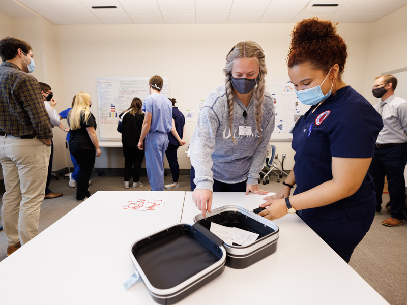 Nursing students Katherine Shell, left, and Julia Fant read the prescriptions for physical therapy for Mrs. Penner's back pain that were included with the antidote to alien mind-swapping.