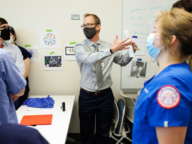 Dr. Ryan Babl debriefs students at the end of the first escape room exercise Thursday.