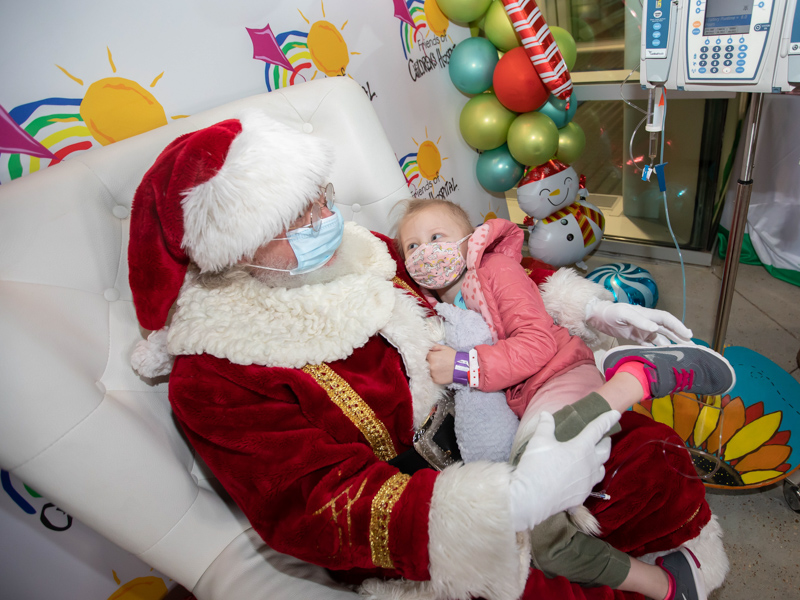 Children's of Mississippi patient Mary Mosley Pickering of Philadephia curls up in Santa's lap during BankPlus Presents Light A Light.