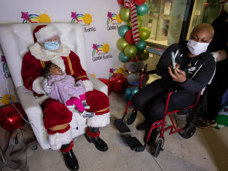 Children's of Mississippi patient Cherish Jones of Laurel visits with Santa as mom Theodeshia Jones takes her photo during BankPlus Presents Light A Light Tuesday.