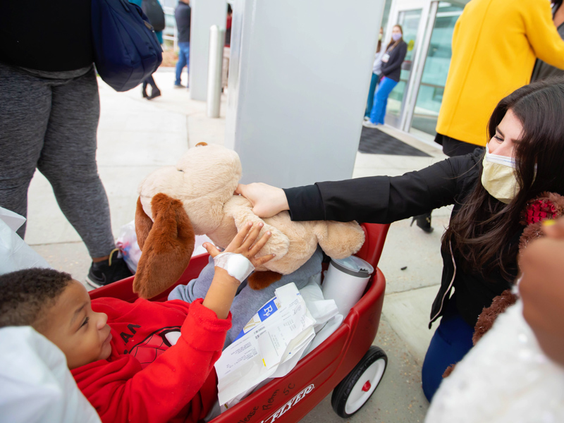 Children's of Mississippi Child Life specialist Kelsey Clark gives patient Damarion Roby a stuffed animal donated by Nicholas Air, a private aviation company, outside Children's of Mississippi.