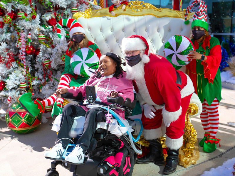 Children's of Mississippi patient DeAsia Scott smiles with Santa and his elves at BankPlus Presents Winter Wonderland.