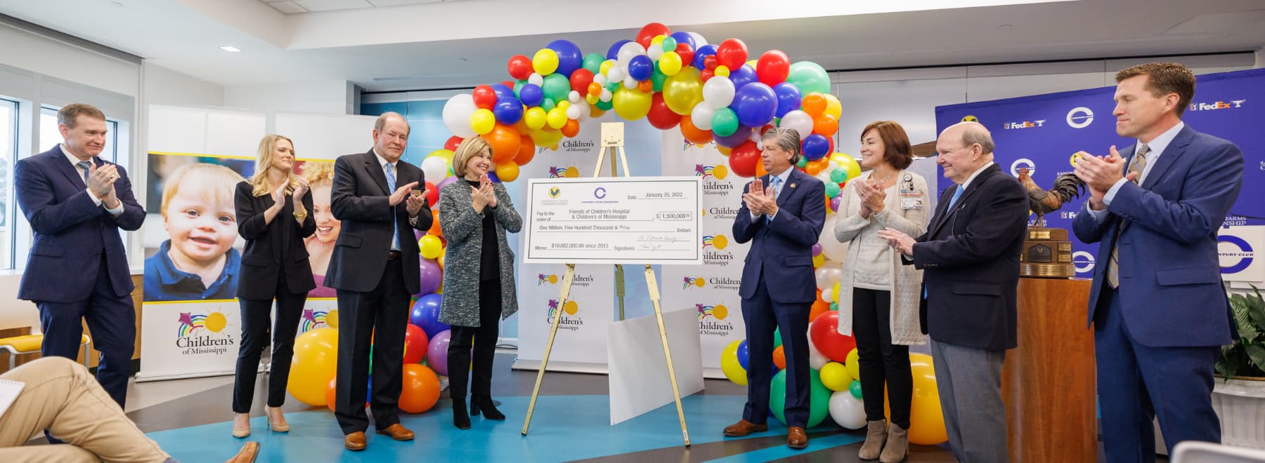 Group of people clapping around large check after reveal.