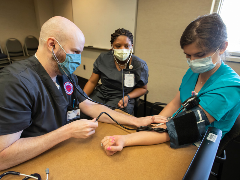 Accelerated BSN students Chris McCormick and De'jai Nichols, center, participate in a skills lab with Anna Solomon, a graduate nursing student.