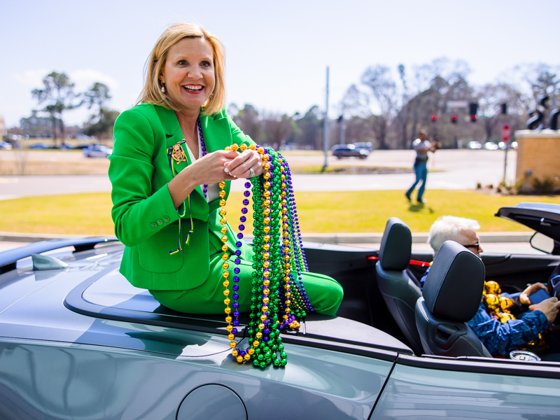 Mississippi First Lady Elee Reeves hands beads to Children's of Mississippi patients and their families during a Mardi Gras parade of Department of Public Safety vehicles Thursday.