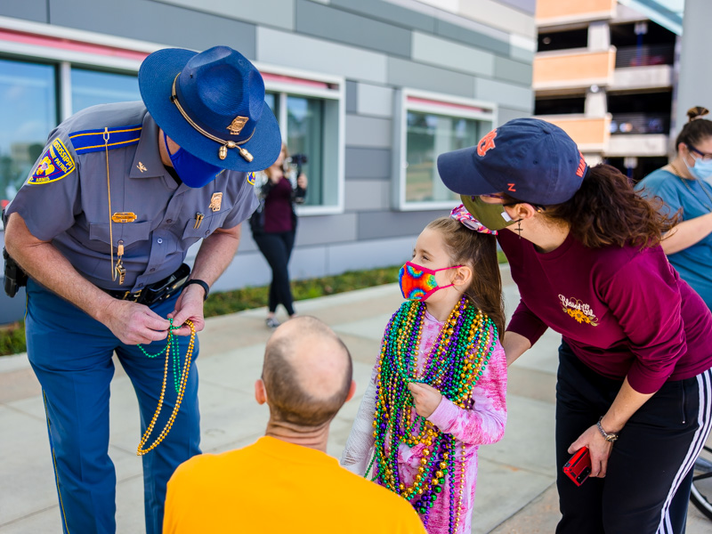 Children's of Mississippi patient Emilia Elkins of Sumrall and her parents, Ash and Stephanie, talk with a Mississippi Highway Patrol officer during a Department of Public Safety Mardi Gras parade Thursday.