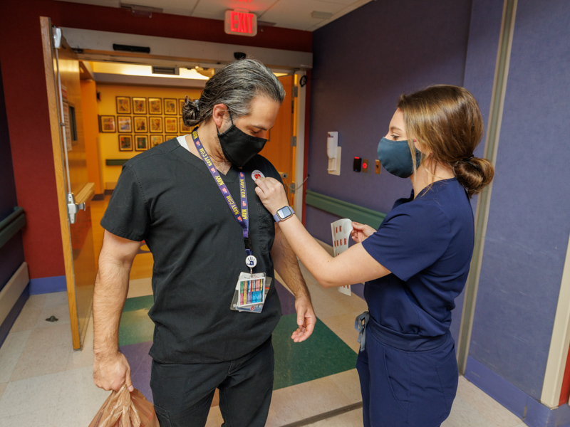 Pharmacist Nate D'Mello gets a sticker from nursing student Mary Kate Sims.