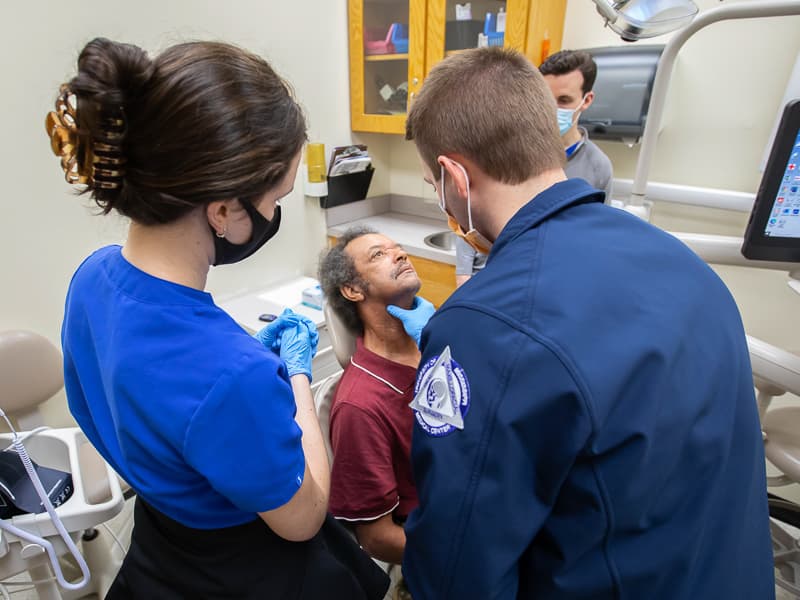 School of Dentistry second-year student Kate Anderson, left, and oral surgery resident Dr. Spencer Remley examine patient Leroy Hobson.