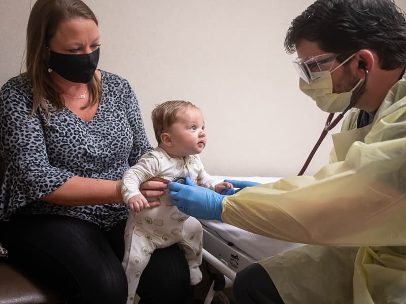 Kasey Finklea holds her grandson, Sutton Finklea, as he gets an exam from Dr. Benji Dillard.