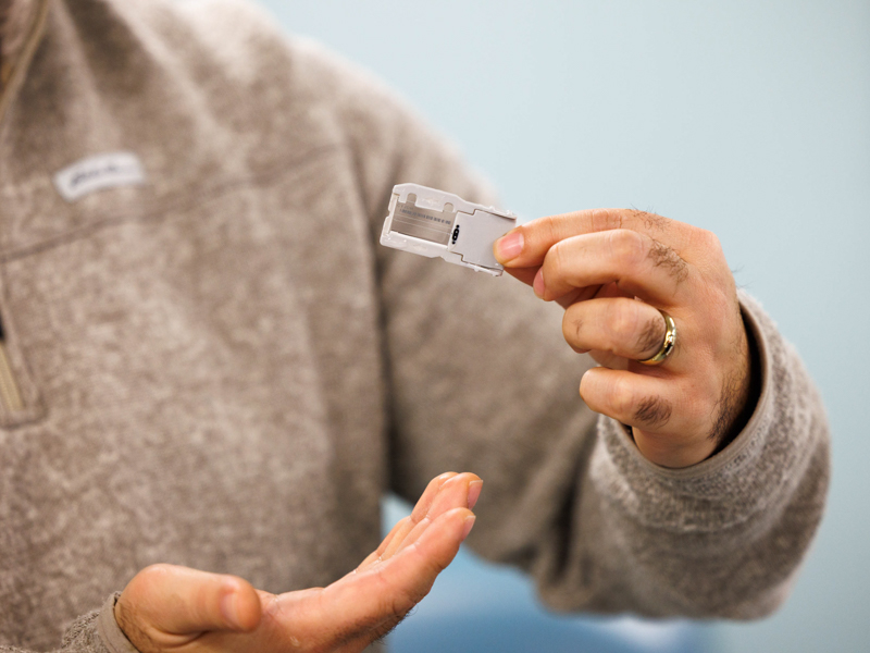 Molecular Pathology Specialist Jake Johnston holds a spent chip used for next-generation sequencing.