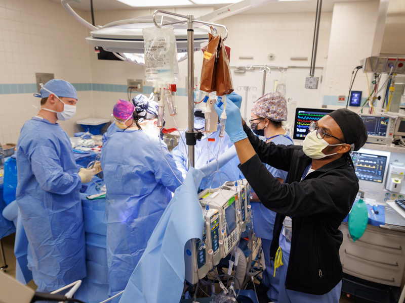 Anesthesiology Resident Dr. Tyler Shack, right, hangs units of blood during a surgical procedure.