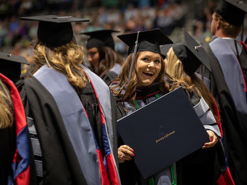 Aimee Pride, Doctor of Occupational Therapy graduate, shows off her degree to family watching from the stands.