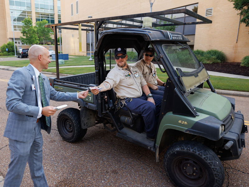Dr. Alan Jones, left, greets building maintenance electrician Shannon Eckles, center, and controls specialist Steve Renner with goodies Thursday morning. Joe Ellis/ UMMC Communications