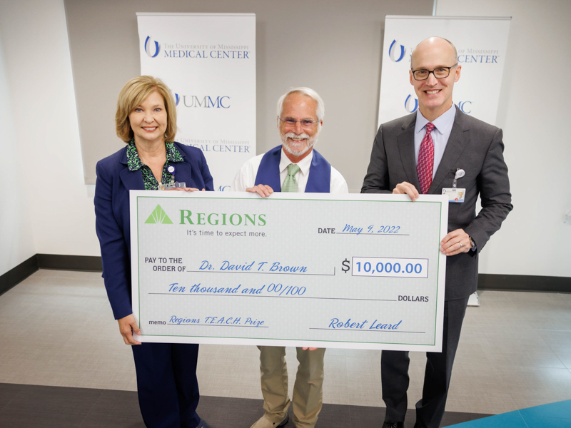 Dr. David Brown, center, is the 2022 Regions TEACH Prize recipient. He received the award from Dr. LouAnn Woodward, vice chancellor for health affairs and Dr. Scott Rodgers, associate vice chancellor for academic affairs. Joe Ellis/ UMMC Communications