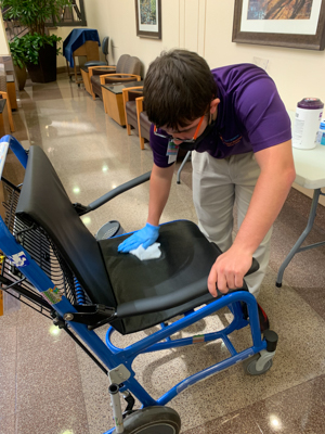 Project SEARCH intern Niel McMillan cleans a transport wheelchair as he makes rounds for Ambassador Services.