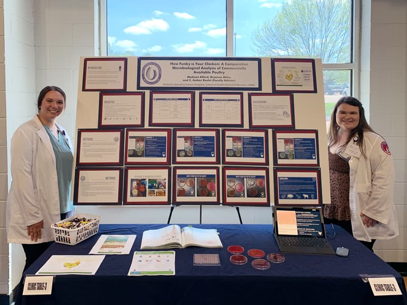 MLS students Bryanna Miles, left, and Madison Alford, right, with their "How funky is your chicken" poster, which was overall winner at SHRP Research Day.