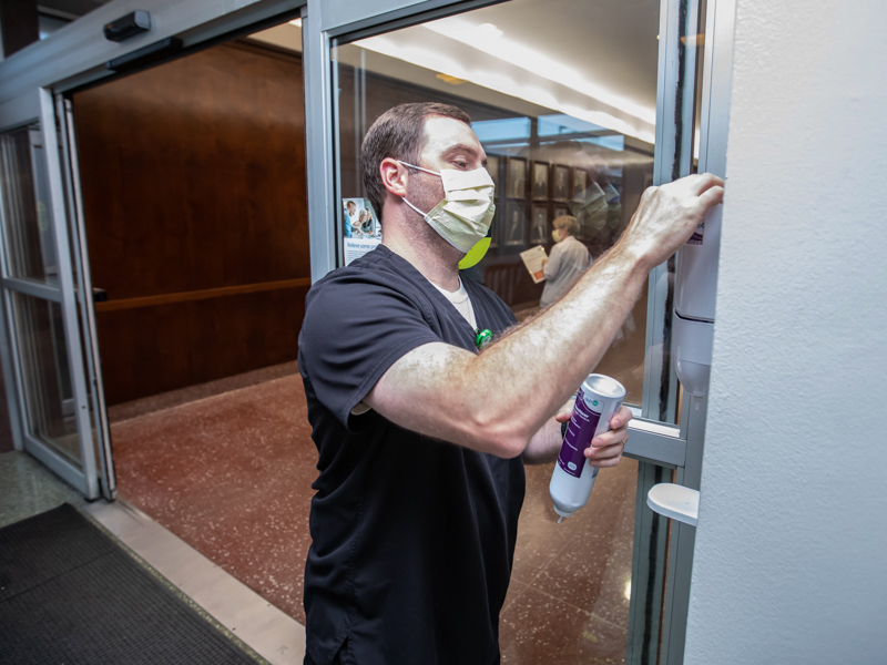 Nursing Resource Team educator and registered nurse Blake Kiker installs a full hand sanitizer container as part of World Hand Hygiene Day. Melanie Thortis/ UMMC Communications